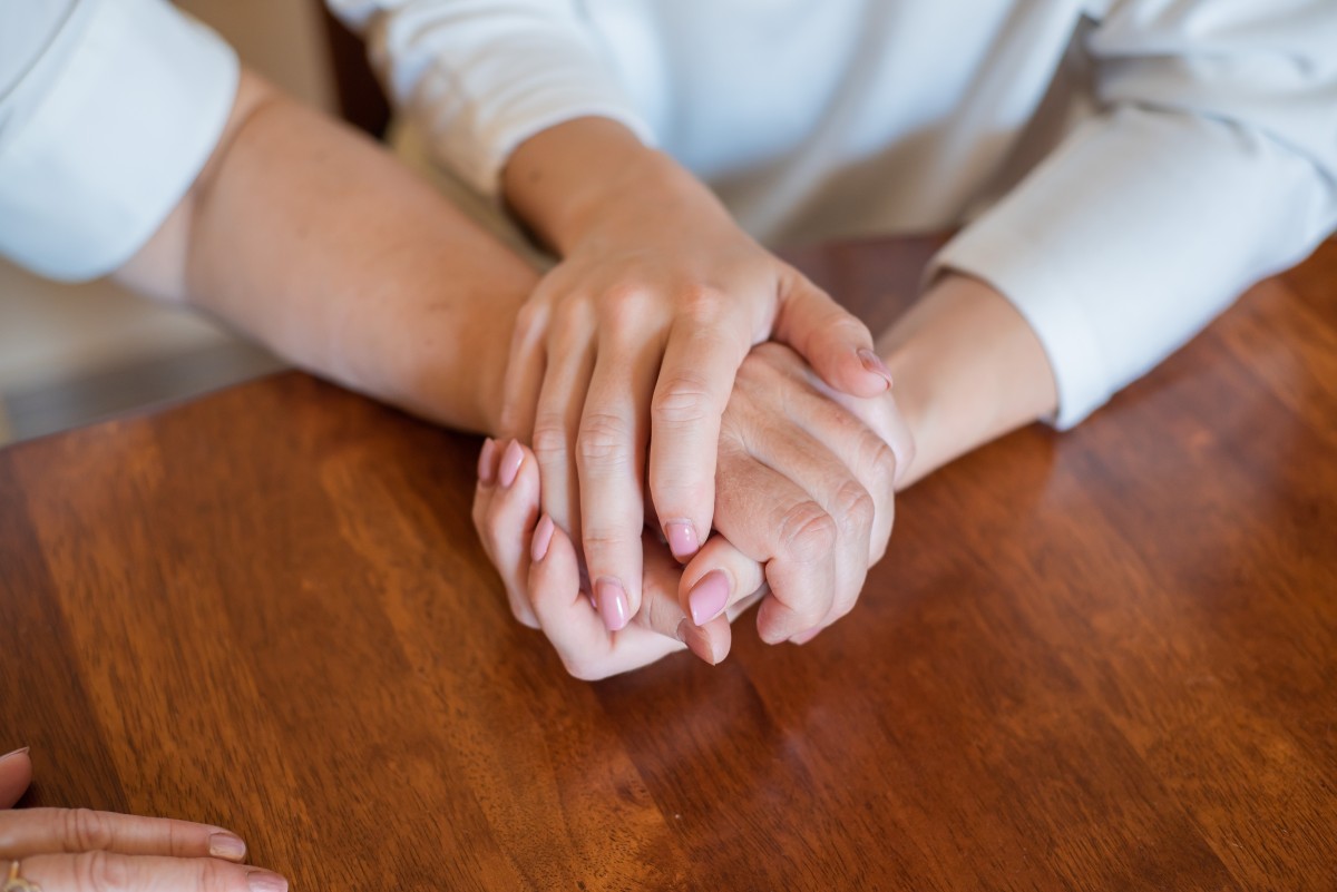 Group holding hands, just hands on a table